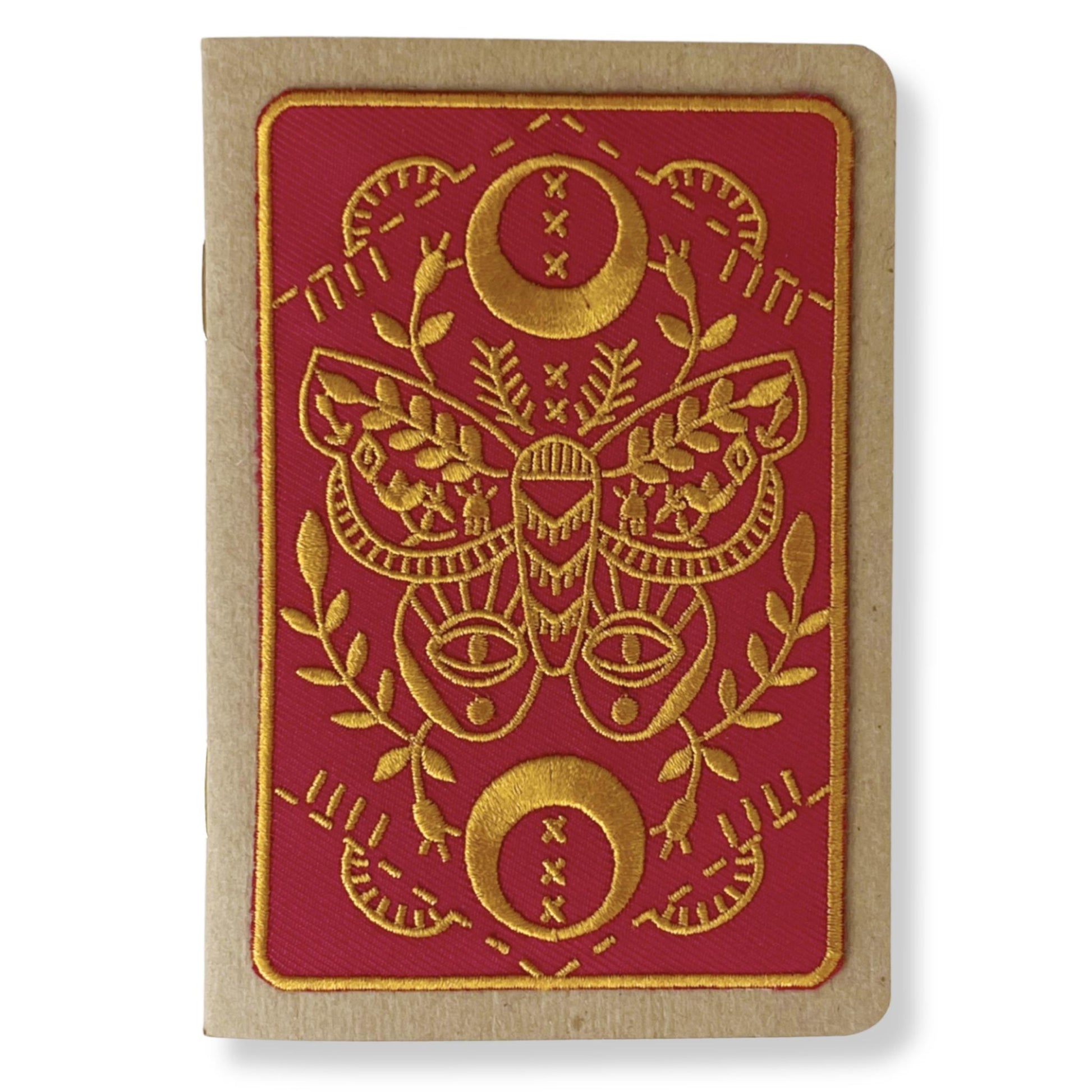 Embroidered patch of gold moth on red background attached to a kraft paper pocket notebook by Rikrack