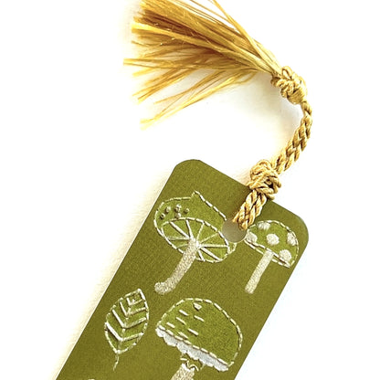 Gold tassel on a light green bookmark with assorted embroidered mushrooms by Rikrack